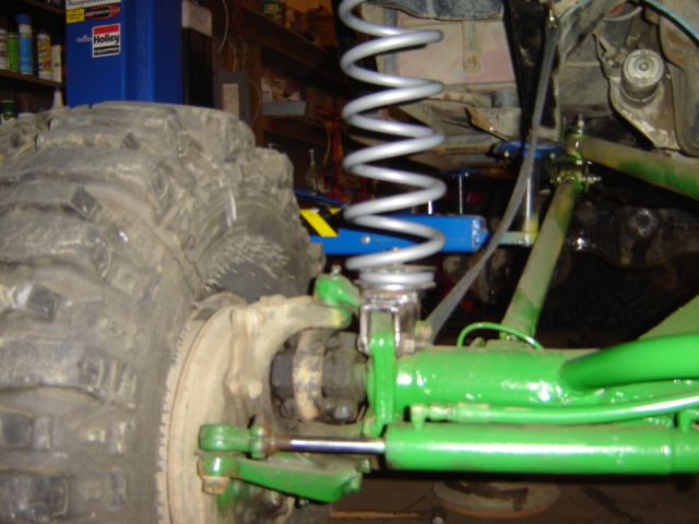 Close-up of a large tire and green suspension components on a vehicle