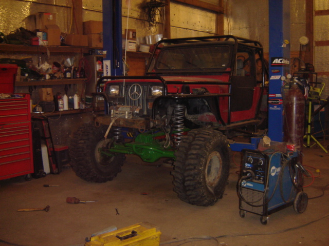 Red off-road vehicle with roll cage, large tires, and Mercedes-Benz grille emblem
