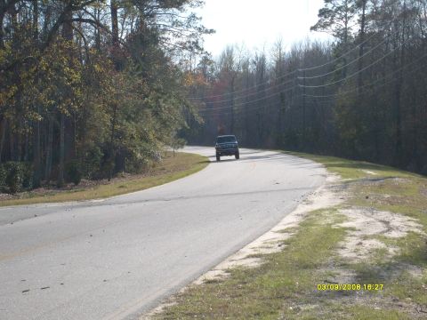 1992 Ford Bronco - A dark SUV is seen driving on a winding road surrounded by trees.