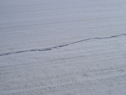 1995 Mercury Grand Marquis - Tire tracks are visible in a snow-covered field, with a crack running through the snow.