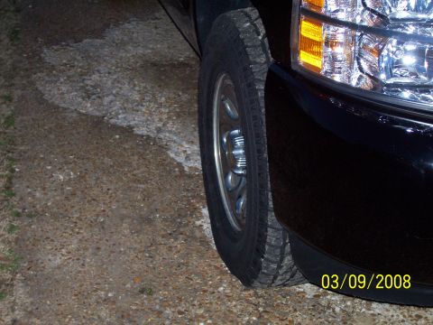 2008 Chevrolet Silverado 1500 - Close-up of a black pickup truck's front corner, showing the wheel and headlight assembly.