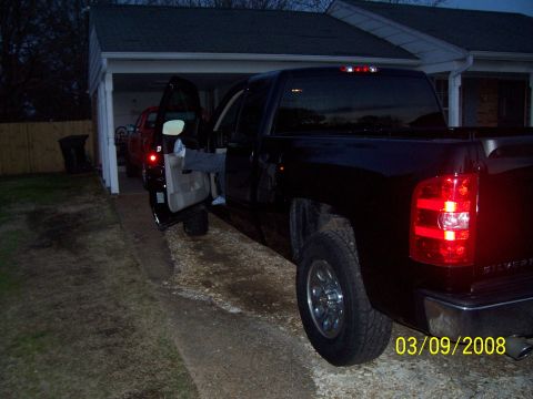 2008 Chevrolet Silverado 1500 - A black 2008 Chevrolet Silverado 1500 pickup truck is parked with the driver's door open, showing a person's legs inside.