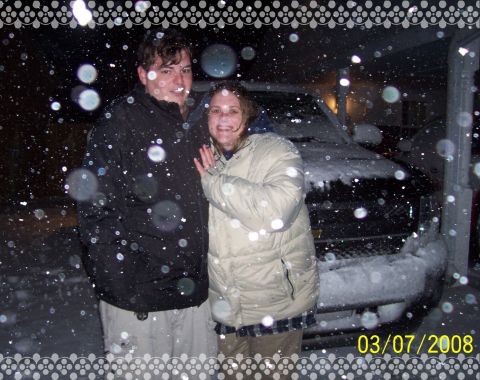 2008 Chevrolet Silverado 1500 - A couple poses in the snow with a dark-colored SUV behind them.
