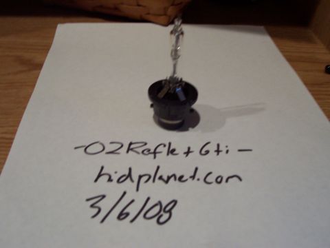 1993 Ford Probe - A headlight bulb is shown on a piece of paper with handwritten text and a website address.