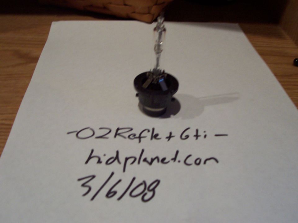Headlight bulb on paper with handwritten text '-02Refle+Gti - hidplanet.com 3/6/09'