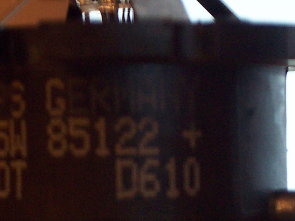 Close-up of a dark part with yellow text that reads '5 G 85122 + D610'