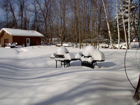 1986 Ford Bronco - A winter scene shows a snow-covered backyard with a small shed and two grills buried under snow.