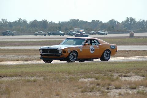 1970 Ford Mustang - Orange 1970 Ford Mustang race car with black hood stripe on track.