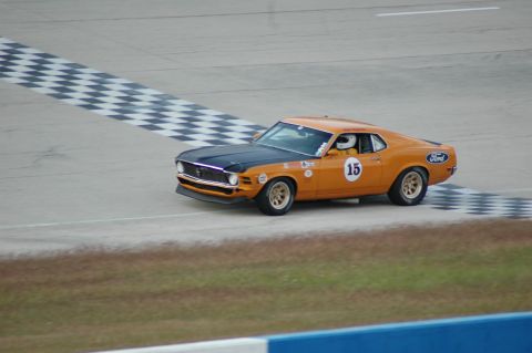 1970 Ford Mustang - A vintage Ford Mustang, number 15, speeds around a race track, approaching the finish line.