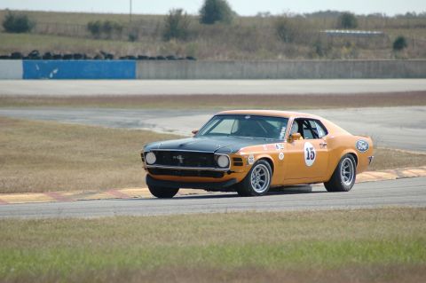 1970 Ford Mustang - A 1970 Ford Mustang race car navigates a turn on a sunny day at the track.