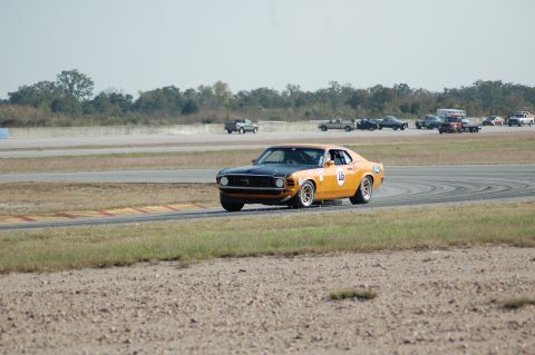 1970 Ford Mustang - A 1970 Ford Mustang, number 15, races on a track with other vehicles in the background.
