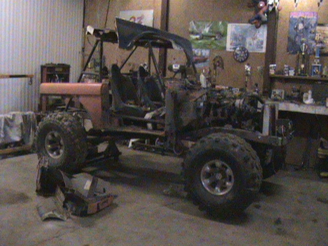 Off-road vehicle chassis with engine and seats, in a garage