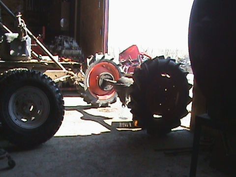 1987 Ford Bronco - Various tractor components, including large wheels and an engine, are visible in a workshop setting.