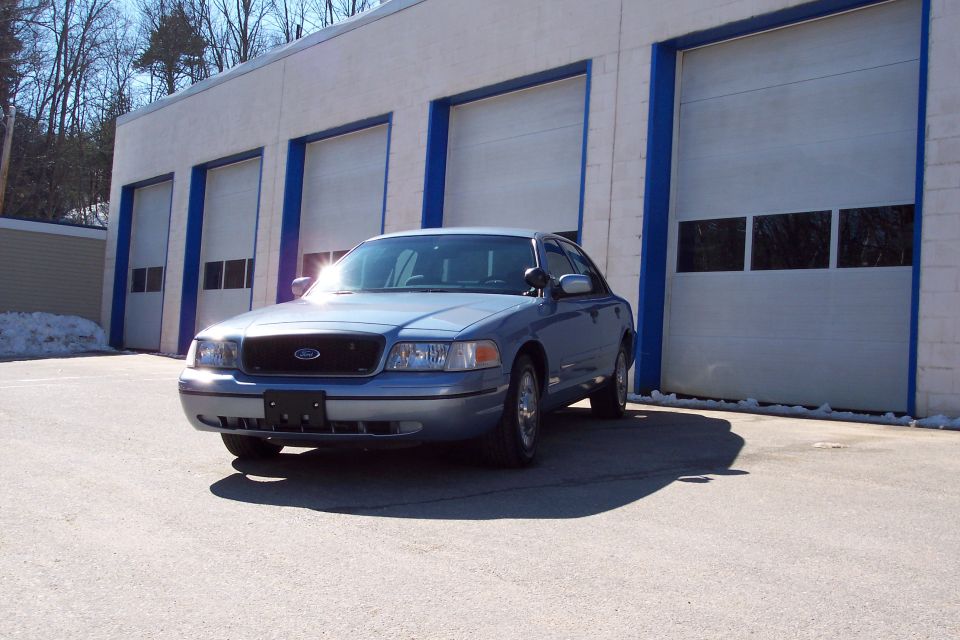 Blue 2001 Ford Crown Victoria parked in front of garage doors