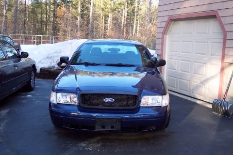 2001 Ford Crown Victoria - A blue 2001 Ford Crown Victoria is parked in front of a garage with snow in the background.