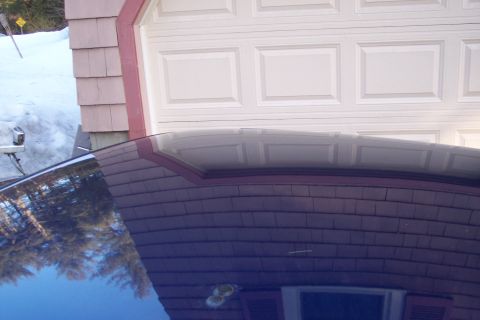 2001 Ford Crown Victoria - Car roof reflection shows trees and sky against a garage door.