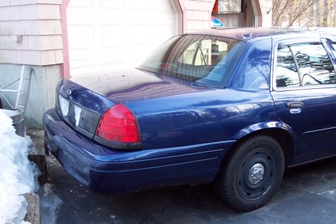 2001 Ford Crown Victoria - Rear view of a blue 2001 Ford Crown Victoria parked in front of a garage.