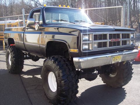 1984 GMC Sierra 3500 - This lifted 1984 GMC Sierra 3500 pickup truck features oversized tires and a prominent side exhaust pipe.