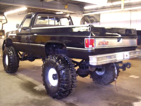 1984 GMC Sierra 3500 - This GMC pickup truck features a lifted suspension and oversized tires, with prominent GMC badging on the rear.