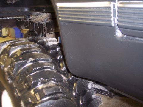 1984 GMC Sierra 3500 - A close-up view of a large, aggressive tire and the underside of a truck's body panel.