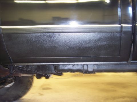 1984 GMC Sierra 3500 - Close-up of the lower body panel and frame of a truck, showing textured material and a horizontal trim piece.