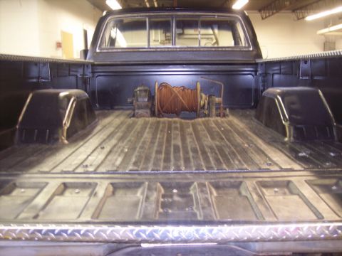 1984 GMC Sierra 3500 - The rear view of a truck bed reveals a winch and rope, with a diamond plate bumper visible at the bottom.
