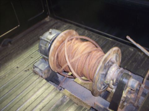 1984 GMC Sierra 3500 - Winch and cable assembly secured in the cargo area of a vehicle.