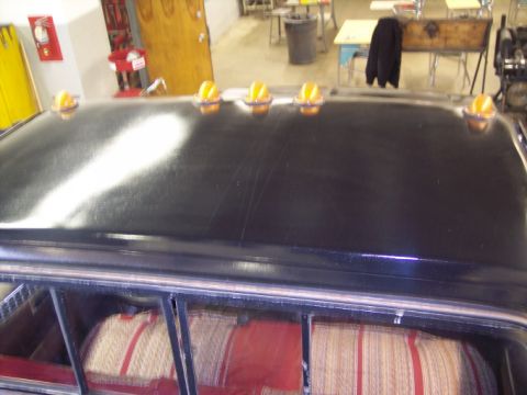 1984 GMC Sierra 3500 - The roof of a black truck is visible, equipped with six amber cab lights and showing part of the interior upholstery.
