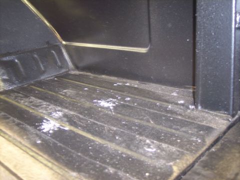 1984 GMC Sierra 3500 - The interior of a truck bed shows a ribbed floor and black walls with some white debris scattered around.
