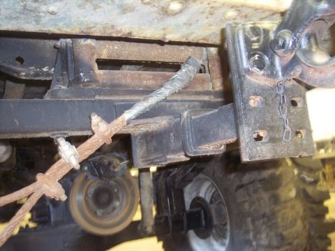 1984 GMC Sierra 3500 - Close-up view of the rear suspension and trailer hitch assembly, showing rusty cables and components.