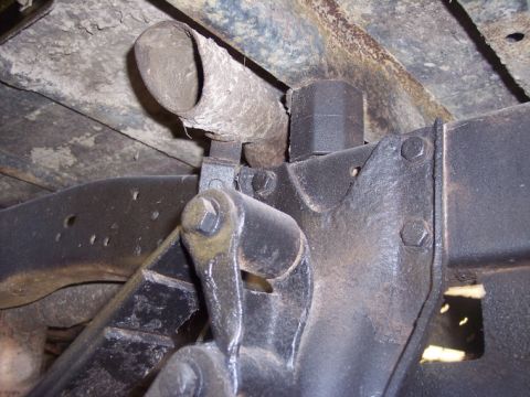 1984 GMC Sierra 3500 - Close-up view of the exhaust pipe and suspension components on the underside of a vehicle.