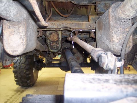 1984 GMC Sierra 3500 - The underside of a truck reveals extensive rust on its suspension and exhaust systems, with a large tire visible.