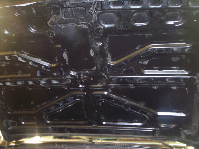 Underside of a black hood with visible structural reinforcements and some wear