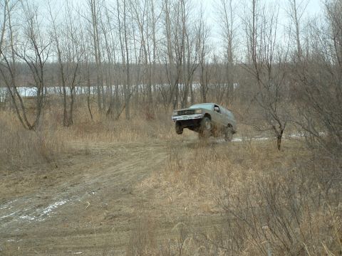 1992 Ford F-350 - A van is captured mid-air on a dirt track, surrounded by a barren, wintry landscape.