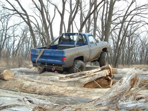 1992 Ford F-350 - This lifted pickup truck is shown off-roading through a challenging course of logs, demonstrating its capabilities.