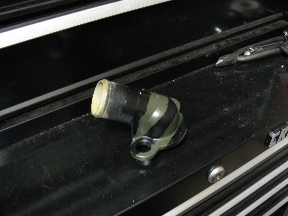 Black and green striped automotive coolant elbow part with a white rimmed opening