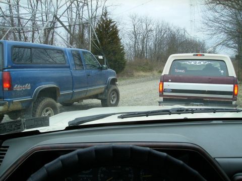 1988 Ford Bronco - A 1987 Ford Bronco is seen from behind, following a blue pickup truck on a dirt road.