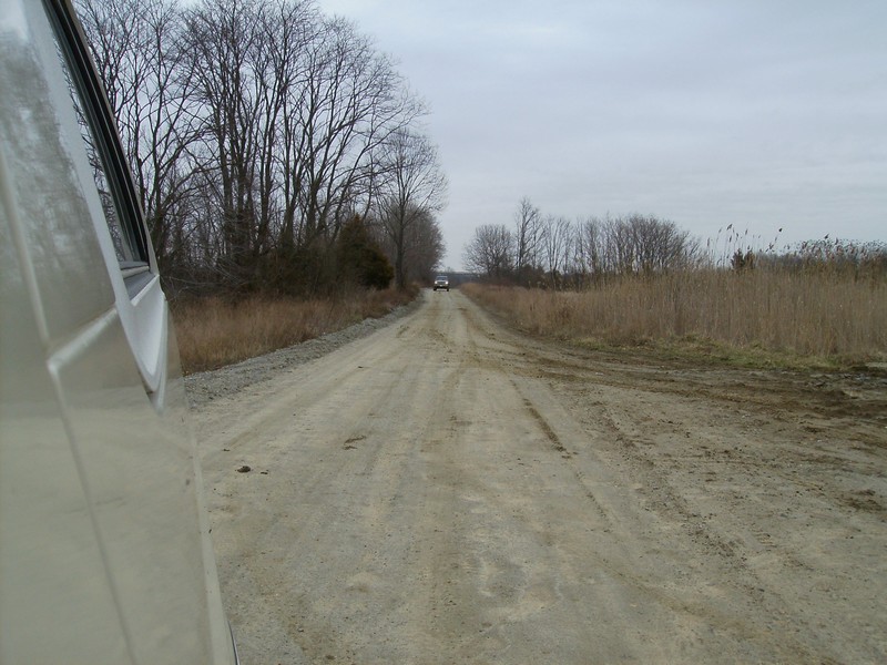 View from a vehicle on a dirt road, another vehicle in the distance