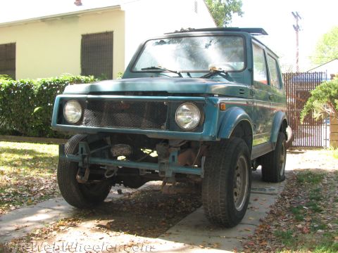 1987 Suzuki Samurai - This 1987 Suzuki Samurai is parked on a concrete driveway in front of a building.