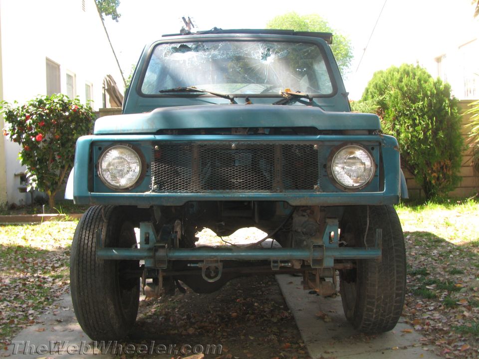 Teal 1987 Suzuki Samurai front view with damaged windshield and off-road bumper