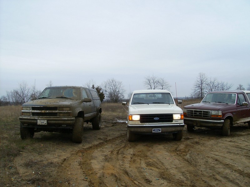 Maroon 1987 Ford Bronco with a white Ford truck and a brown SUV in mud