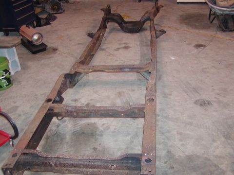 1991 Ford Bronco - A heavily rusted vehicle frame sits on a concrete floor in what appears to be a garage or workshop.