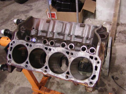 1991 Ford Bronco - An engine block rests on a stand, revealing its internal cylinder structure and signs of wear.