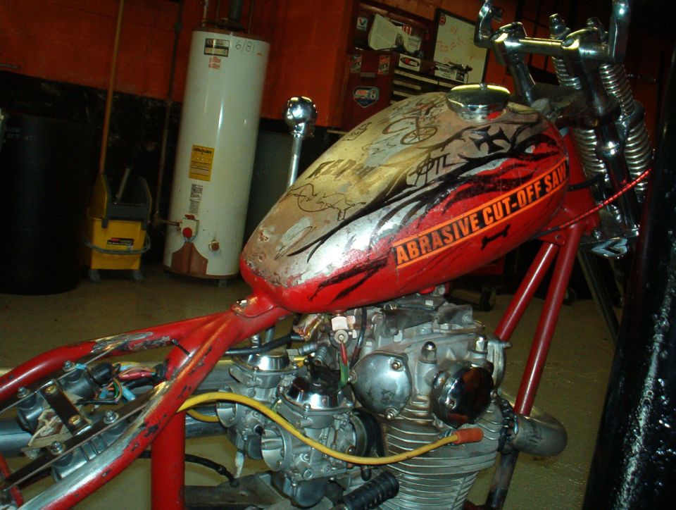 Red custom motorcycle frame with engine and fuel tank, side view