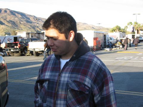 1986 Ford Bronco - A man stands in a parking lot with trailers and vehicles behind him under a bright sky.
