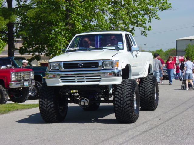 White lifted Toyota pickup on huge tires at an outdoor car show