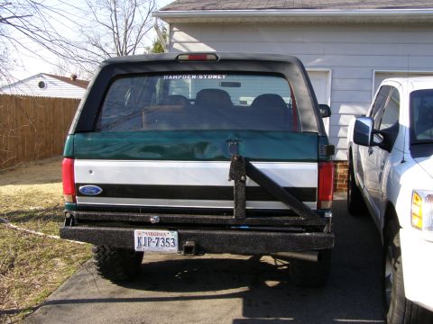 1993 Ford Bronco - The rear of a green and white Ford Bronco is visible next to a white pickup truck.