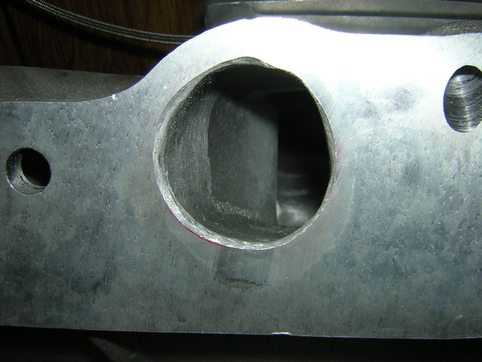 Close-up of a metal cylinder head intake port with visible machining marks