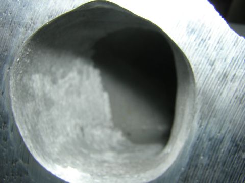 1979 Ford Bronco - A detailed view of a metal engine intake port, showing its internal texture and shape.
