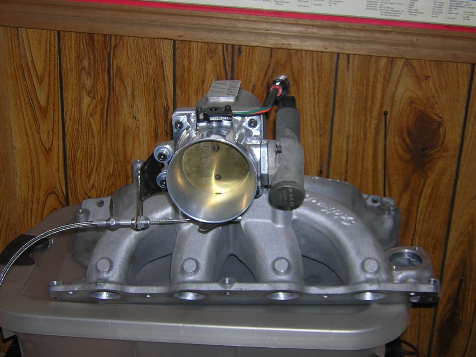 Aluminum EFI intake manifold with a large aftermarket throttle body sitting on a tote